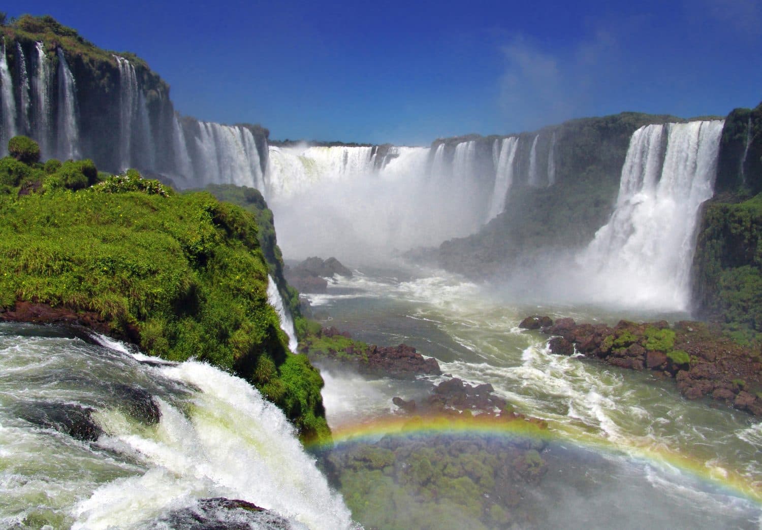 Mist and water cascading over rocky cliffs at Iguazu Falls.
