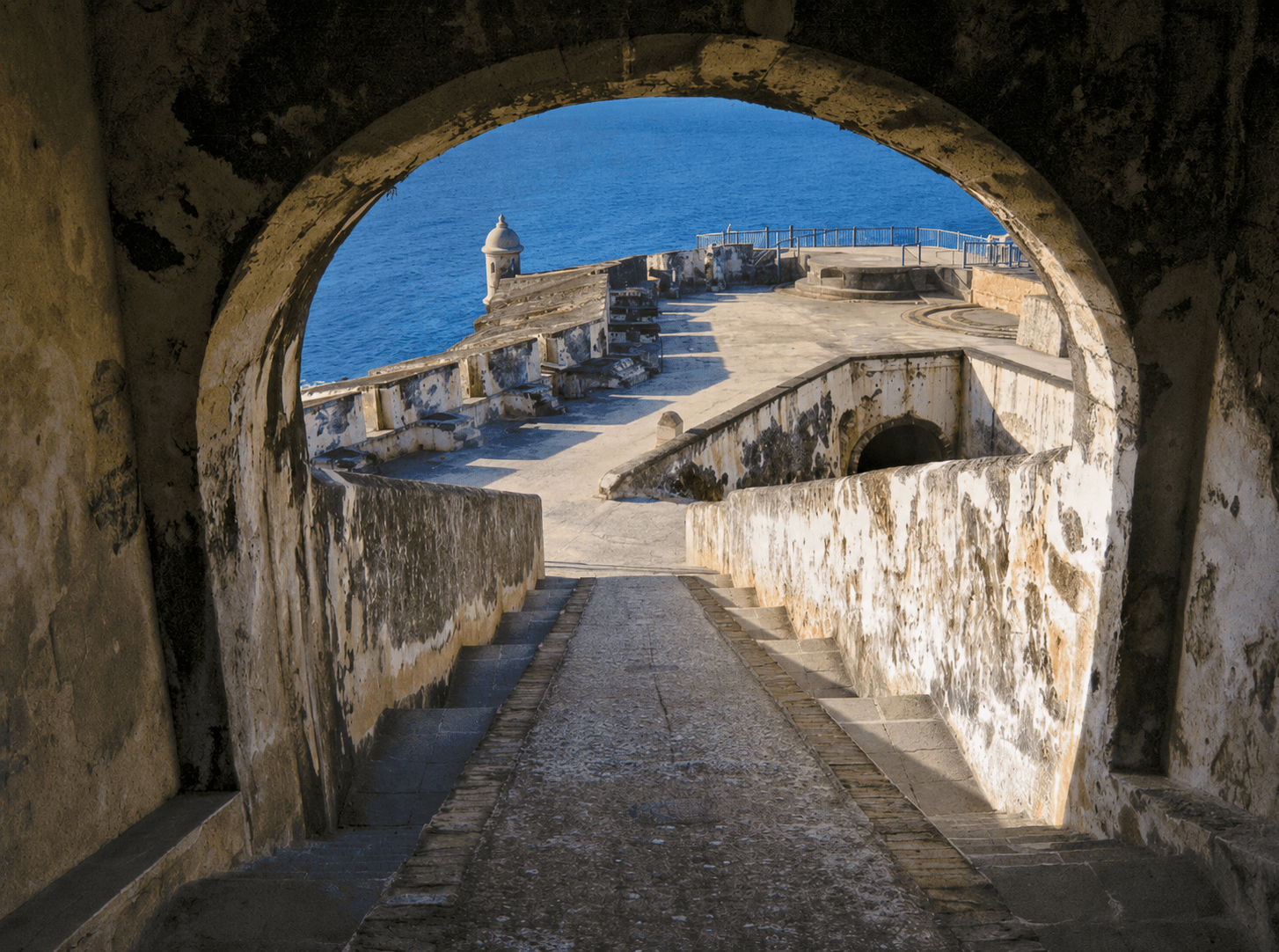 San Juan's historic coastal fortifications framed by a stone arch above the Atlantic.